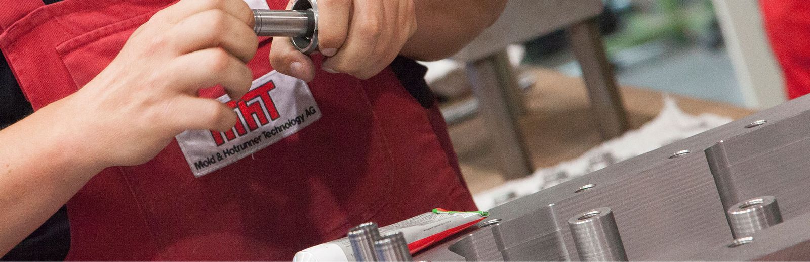 Técnico de MHT trabajando en un componente de un molde de inyección, fotografía oficial del fabricante.
